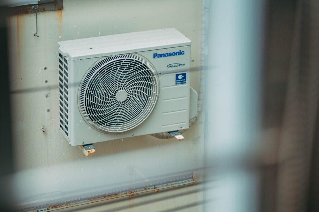 pexels-photo-27134985 Air conditioner unit mounted outdoors on a building wall, showcasing modern HVAC technology.
